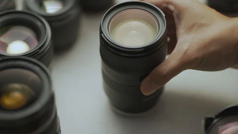 A hand putting down the lens of the camera between another lens. Video stock 128407589