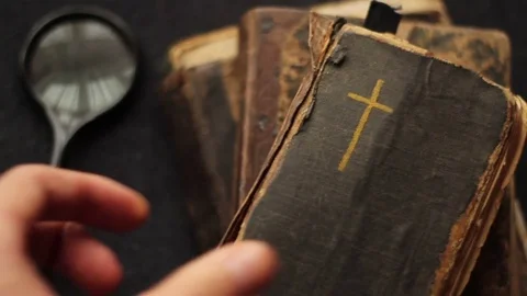Hand putting down old religious books. Video stock 73829357