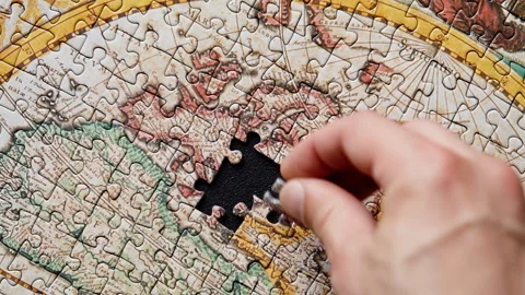 Hand putting down puzzle piece closeup. Jigsaw assembling on black background Stock Footage 332310269