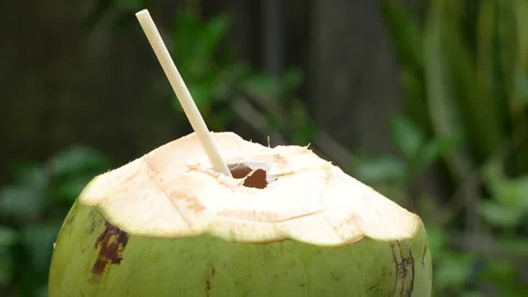 Hand Putting Eco-Friendly Straw into Fresh Coconut Drink Outdoors Stock Footage 319907108