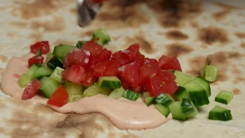 Hand putting fresh tomatoes on flatbread pita Stock Footage 262214850
