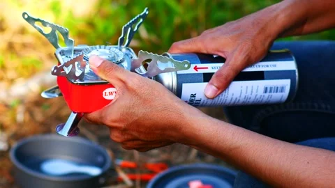 Hand putting gas bottle on mini stove for cooking Stock Footage 240529558