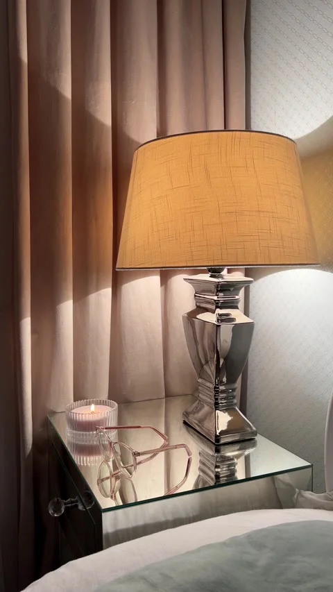 Hand putting glasses on mirrored nightstand with lamp in modern classic bedroom Video stock 346094774