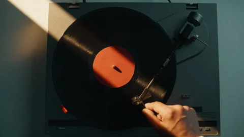 Hand putting gramophone needle on black vinyl disc in evening light closeup. Stock Footage 332622964