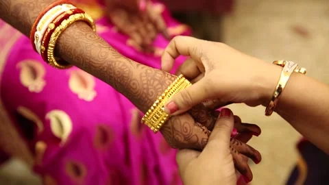 Hand putting helping bride wearing bangle bracelet jewellery in marriage wedding Stock Footage 147683562