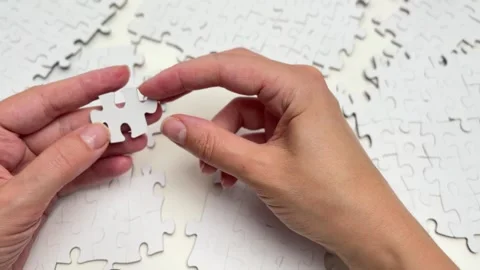 Hand putting the last piece of a white jigsaw puzzle together Stock Footage 336627001