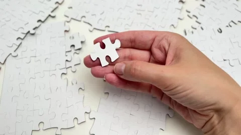 Hand putting the last piece of a white jigsaw puzzle together Stock Footage 336627042