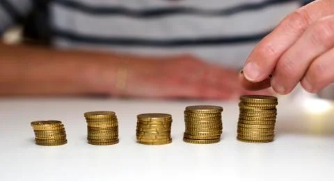 Hand putting money on stack Stock Photos