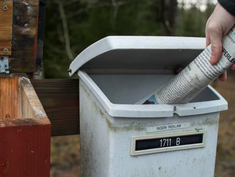 A hand putting newspaper into postbox Stock Photos