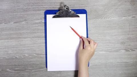 Hand putting o orange pen on wood gray background Stock Footage 314775127