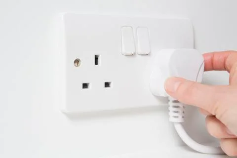 Hand putting plug into electricity socket Stock Photos