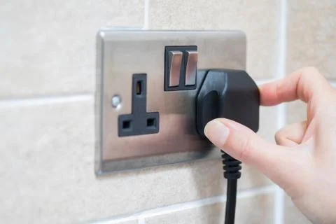 Hand Putting Plug Into Electricity Socket Foto stock