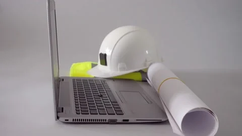 Hand putting rolled plans on a table with helmet and laptop, 4k Stock Footage 202138832