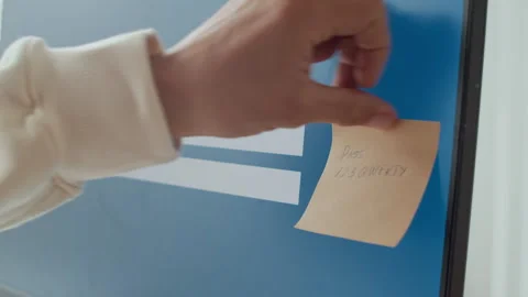 Hand Putting Sticker with Password Information on Computer Screen Stock Footage 303560524