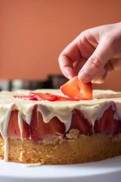 Hand Putting Strawberry on Cake Stock Photos