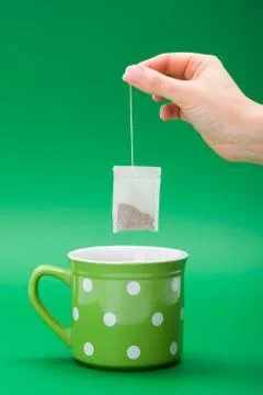 Hand putting a tea bag into Stock Photos