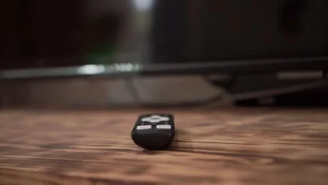 Hand putting TV remote next to mobile phone, blurred screen background, Stock Footage 342635575