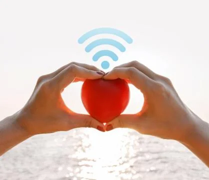 Hand raised up red heart over the sea with wifi icon Stock Photos