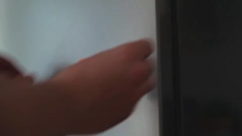 A hand reaches for a door handle before placing a note labeled hungry on a wall. Video stock 339096391