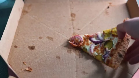 A hand reaches for the last slice of pizza in an empty box. The box shows sauce 库存影片 338290102