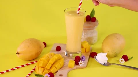 Hand Reaches for Mango Smoothie on Bright Yellow Background Stock Footage 321524178