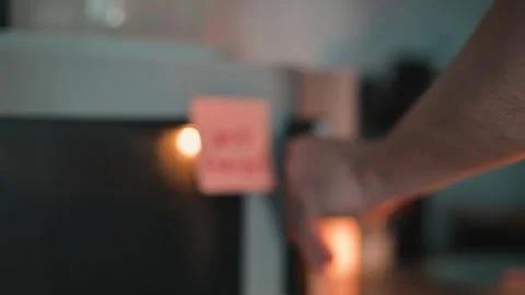 A hand reaches for the microwave door in a kitchen setting, where sticky notes Stock Footage 339096672