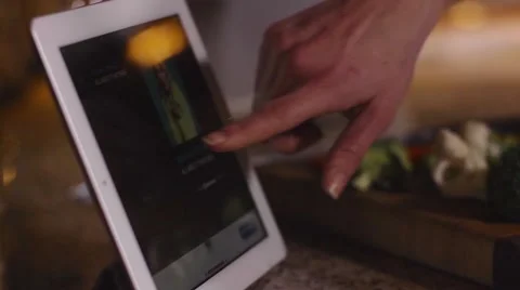 Hand reaches out to control tablet computer while preparing dinner in kitchen Stock Footage 47780489
