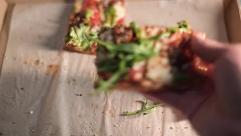 A hand reaches out to grab a slice of pizza topped with fresh greens and Stock Footage 339005333