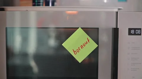 A hand reaches out to remove a sticky note burnout from the microwave while the Stock Footage 339096696