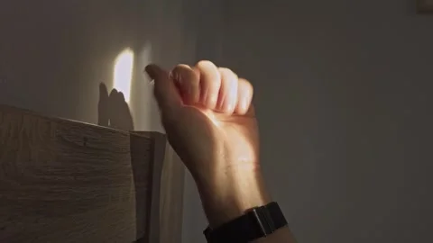 A hand reaches out into a warm beam of morning sunlight, casting a shadow on Stock Footage 344162095