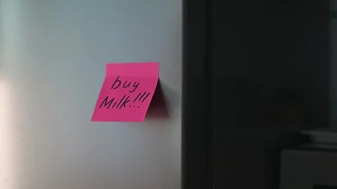 A hand reaches for the refrigerator door while a bright pink note is visible on Stock Footage 339096475