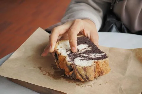 Hand reaches for a slice of marbled bread on paper Stock Photos
