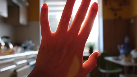 Hand reaches for sun in sunset sky, grass and clouds below Stock Footage 266153650