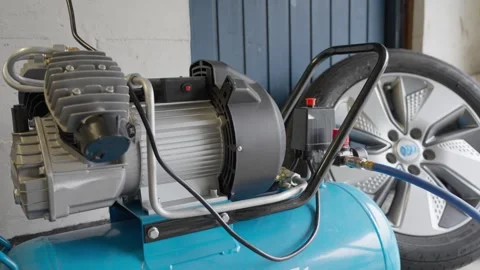 Hand reaches to switch off air compressor in garage, close up static shot 動画素材 332707423