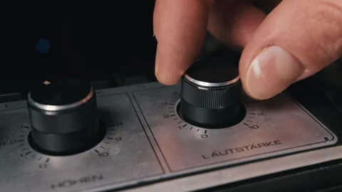 Hand Reaching to Adjust Volume Dial on a Vintage Stereo Amplifier Video stock 332551278
