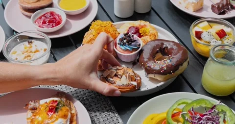 Hand reaching for almond bun on diverse breakfast platter Видео 334408367