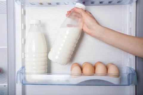 Hand reaching for bottle of milk in refrigerator Stock Photos