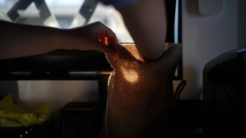 Hand reaching into a burlap sack, illuminated by soft natural light from a Stock Footage 313540836