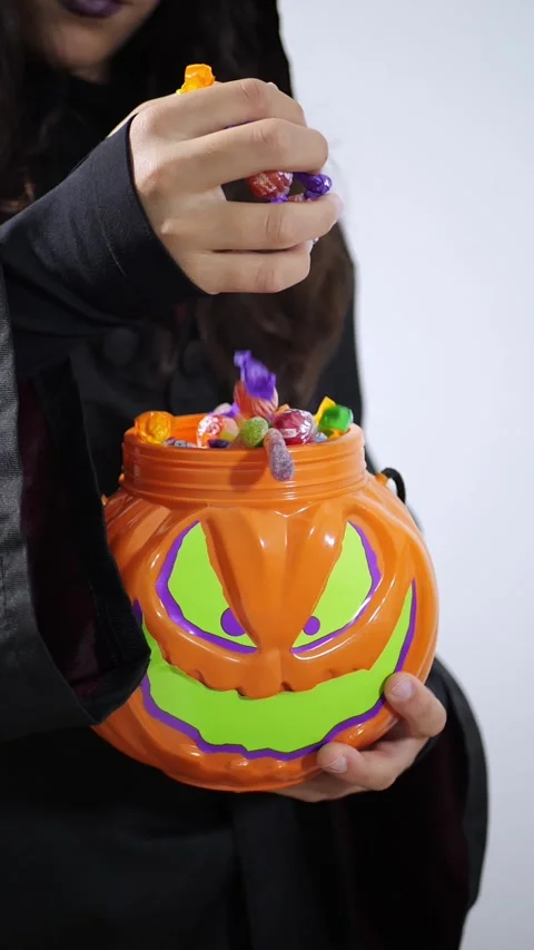 Hand reaching for candy in a Halloween jack-o-lantern pail Stock Footage 342521626