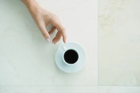 Hand reaching for coffee cup, viewed from directly above 스톡 사진