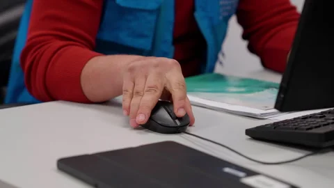 Hand reaching for computer mouse on desk, showcasing focused interaction with Stock Footage 323232056