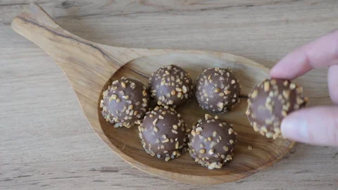 Hand is reaching for delicious chocolate snack on a wooden dish Stock Footage 342501172