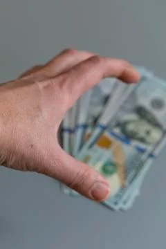 Hand reaching for dollars on gray background. vertical photo Stock Photos