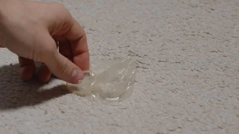 A Hand Reaching Down To Pick Up A Used Condom From A Light-Colored Carpet, Close Stock Footage 301168706