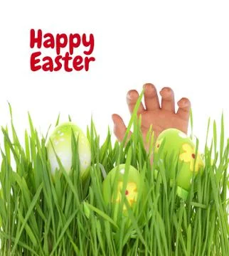 Hand reaching for Easter egg on green grass Stock Photos