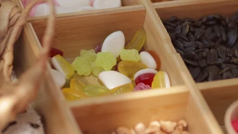 Hand Reaching for Gummy Candy from Container with Sweets and Seeds on Picnic Stock Footage 298893020