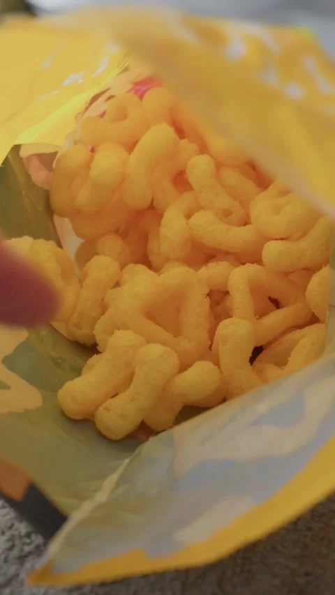 Hand Reaching Inside Open Bag of Yellow Cheese Puff Snacks Indoors Stock Footage 341996018