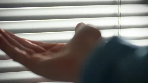 Hand reaching for light through blinds at home during day Stock Footage 304276717