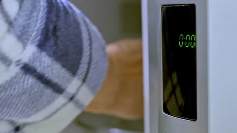 Hand Reaching Into Microwave With Green Timer Display In Modern Kitchen Stock Footage 322098055