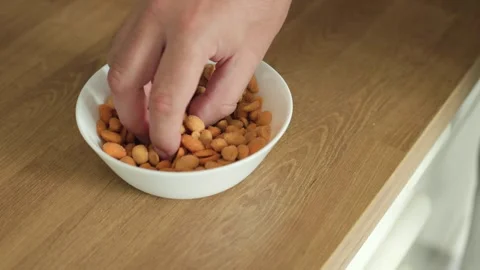 Hand Reaching for Mixed Roasted Nuts in Bowl Video stock 346809865
